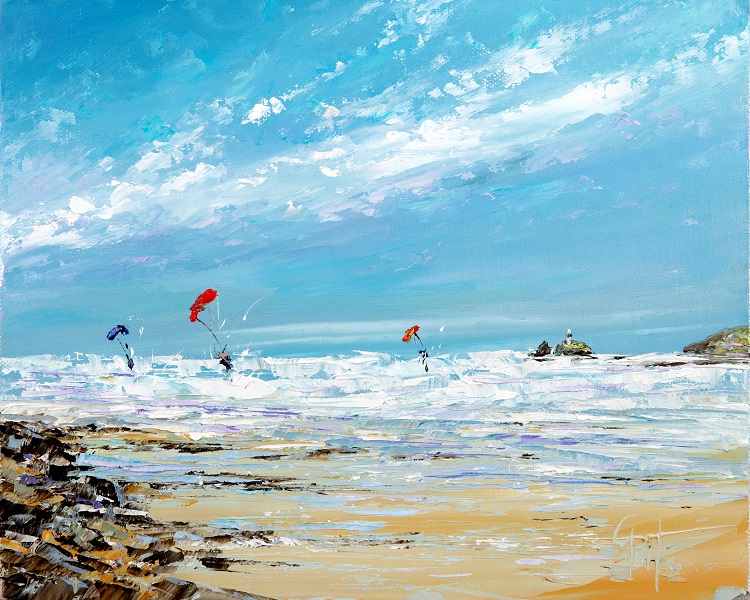 A vibrant painting and print available depicting a beach scene of Hayle Beach and Godrevy Lighthouse, featuring colourful kitesurfers against a bright blue sky, with waves crashing on the shore and rocky outcrops in the foreground.